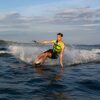 Junger Mann auf Wasser-Ski trägt leuchtend grüne Schwimmweste für Sicherheit und Komfort beim Wassersport, ideal für Aktivitäten wie Wakeboarden, SUP und Kanu fahren.