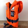 Orangefarbene Secumar Rettungsweste Bravo für Kinder von 20 bis 30 kg mit hochwertigem Auftrieb von 100 N, reflektierenden Streifen und stabilem Clip-Verschluss.